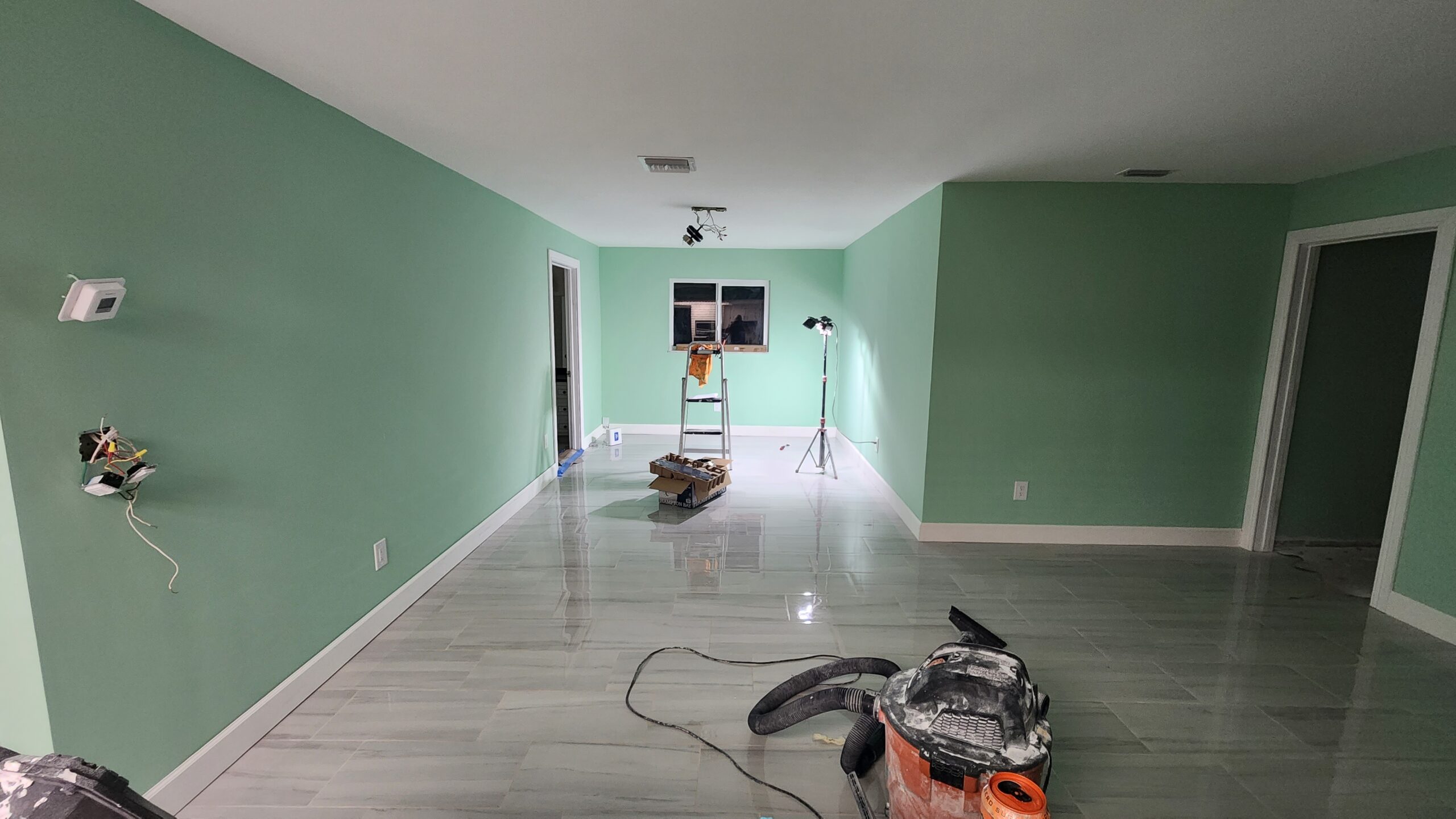 Completed interior renovation with leveled flooring, new tile installation, drywall, and fresh paint.