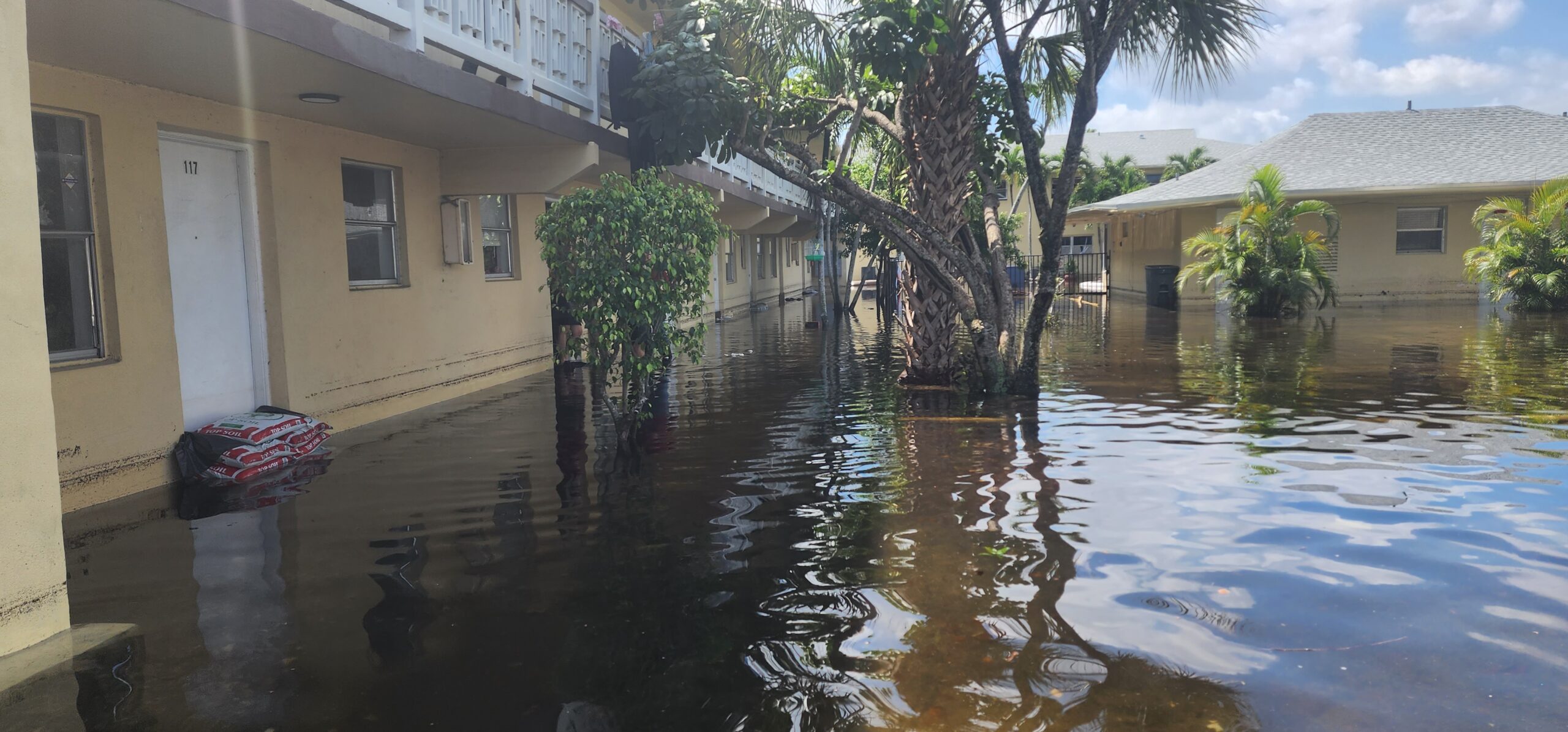 Exterior of residential community flooded with standing water after storm, showing significant property impact.