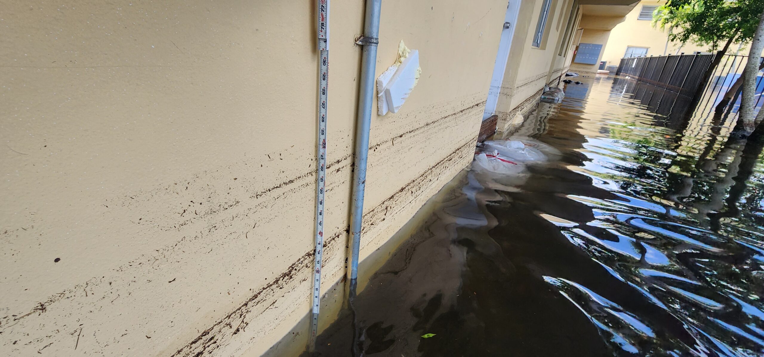 Close-up of building exterior showing high-water flood line and damage assessment markings.
